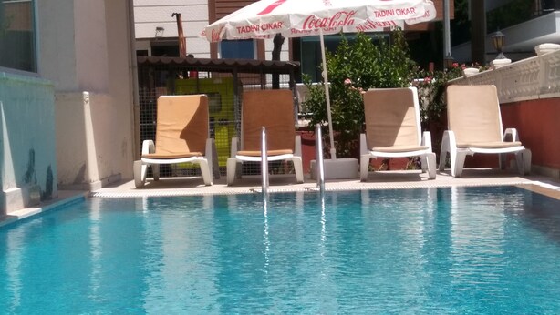 Una piscina al aire libre, sombrillas, sillones reclinables de piscina