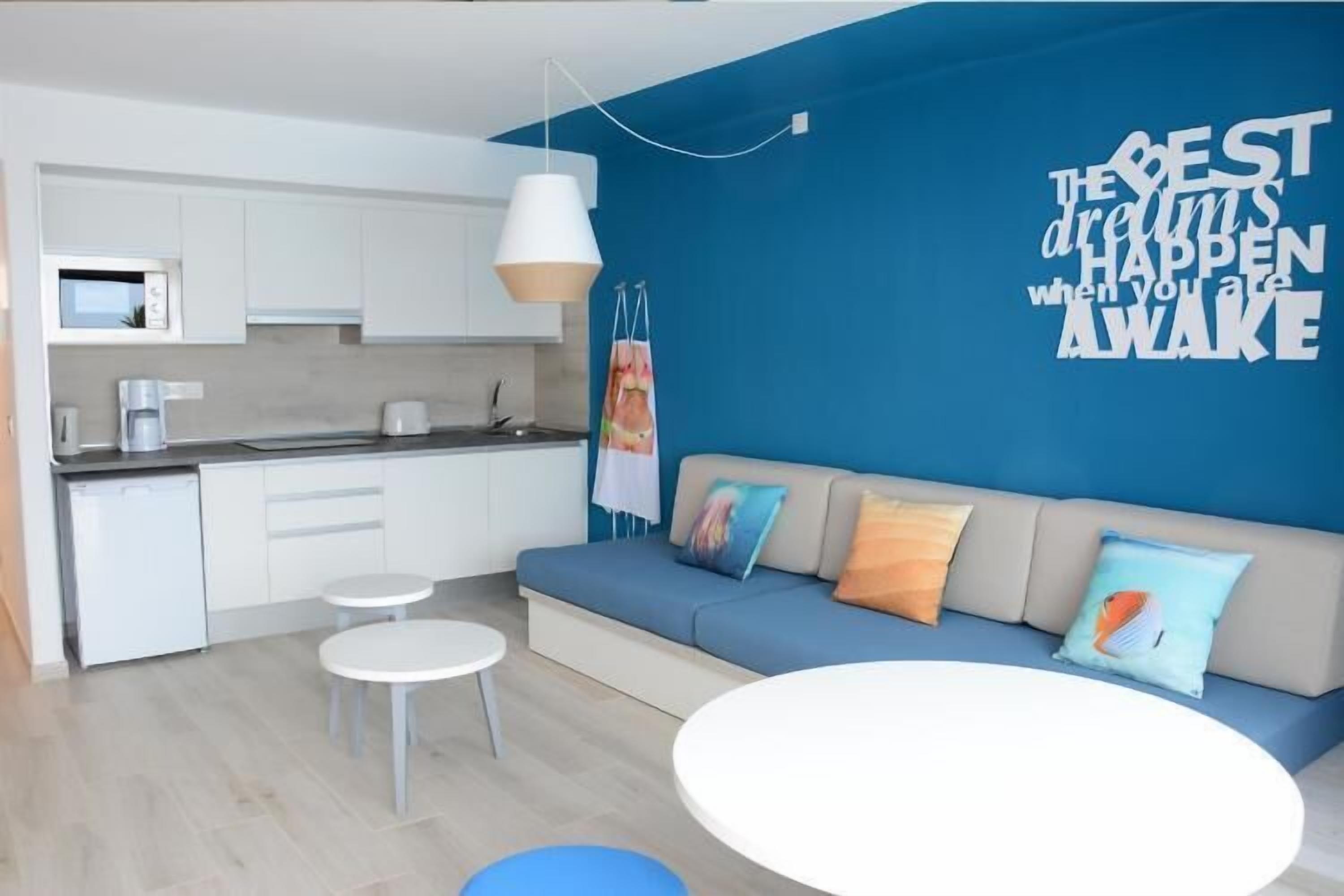 A modern living space with a kitchen, a sofa, and a round table.