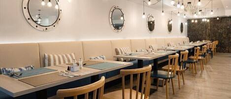A restaurant with round mirrors on the walls, wooden chairs, and tables with placemats.
