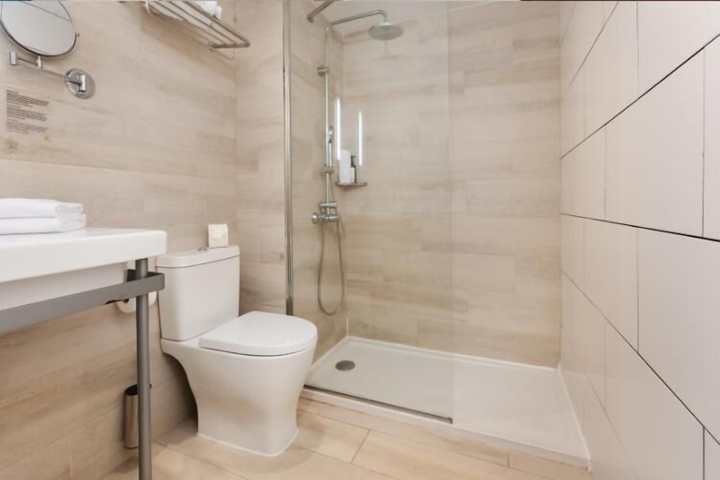 A modern bathroom with a toilet, sink, and shower.