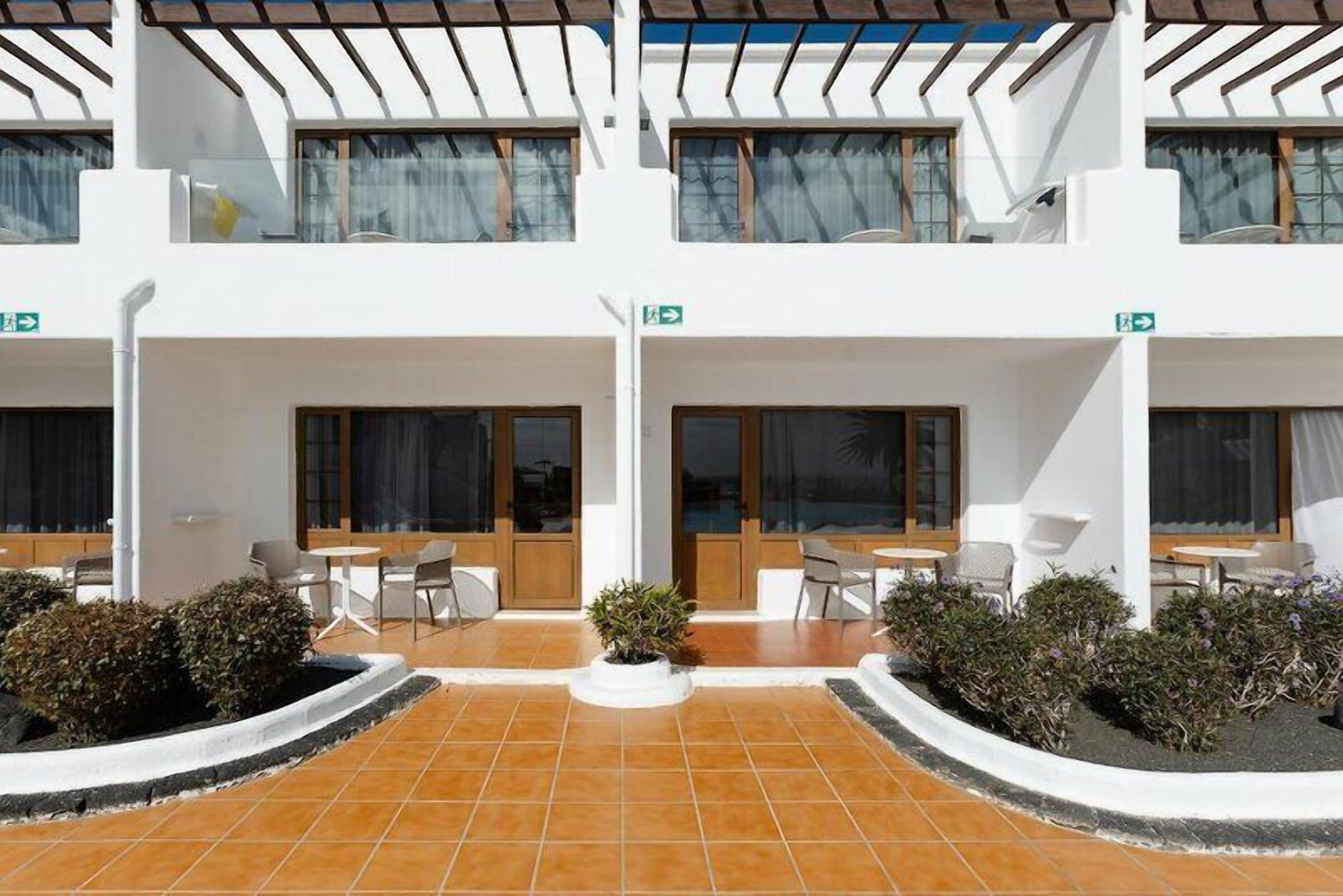 Un hotel con una terrazza, arredata con sedute all'aperto e piante in vaso.