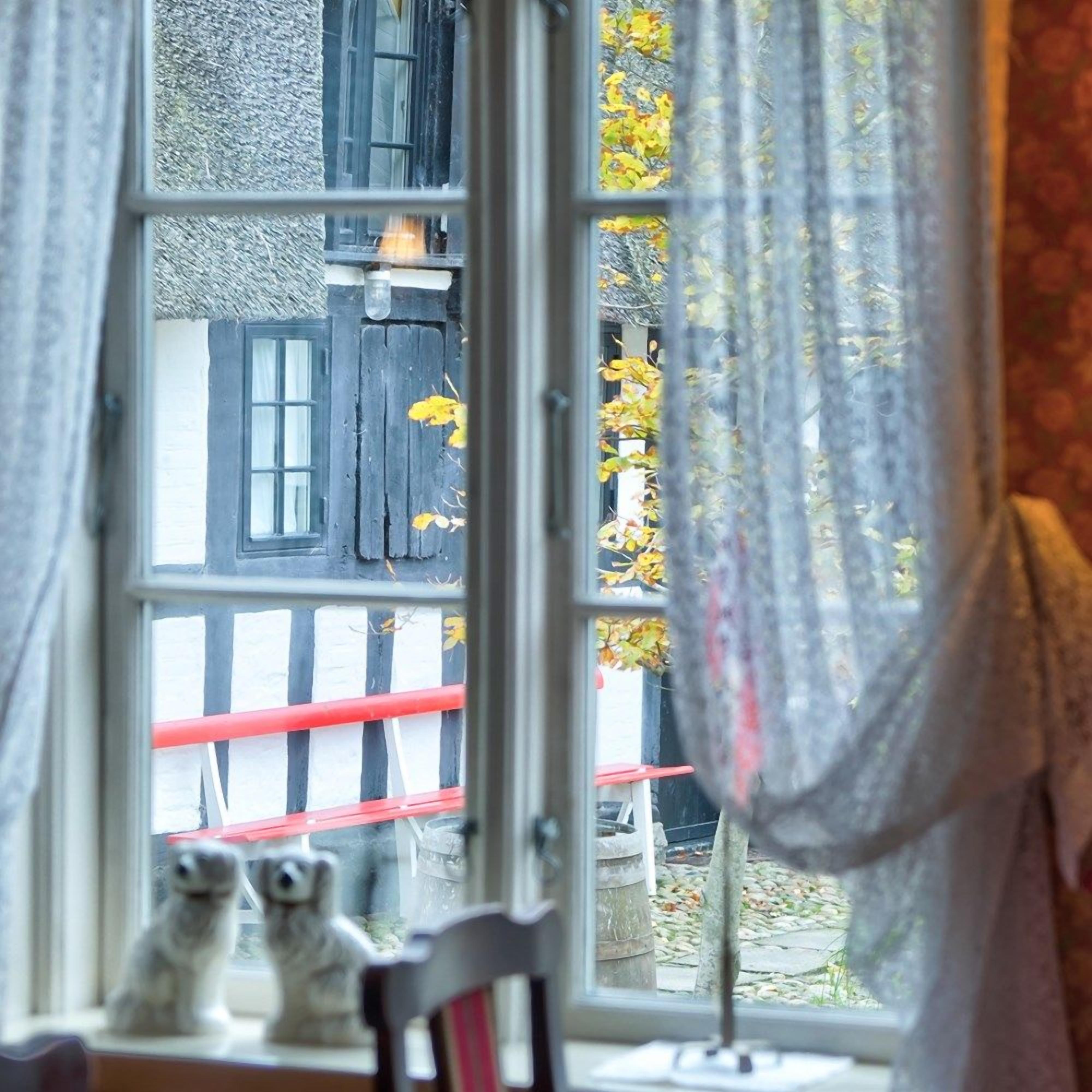 Una ventana con vista a un edificio y una baranda roja en el exterior.