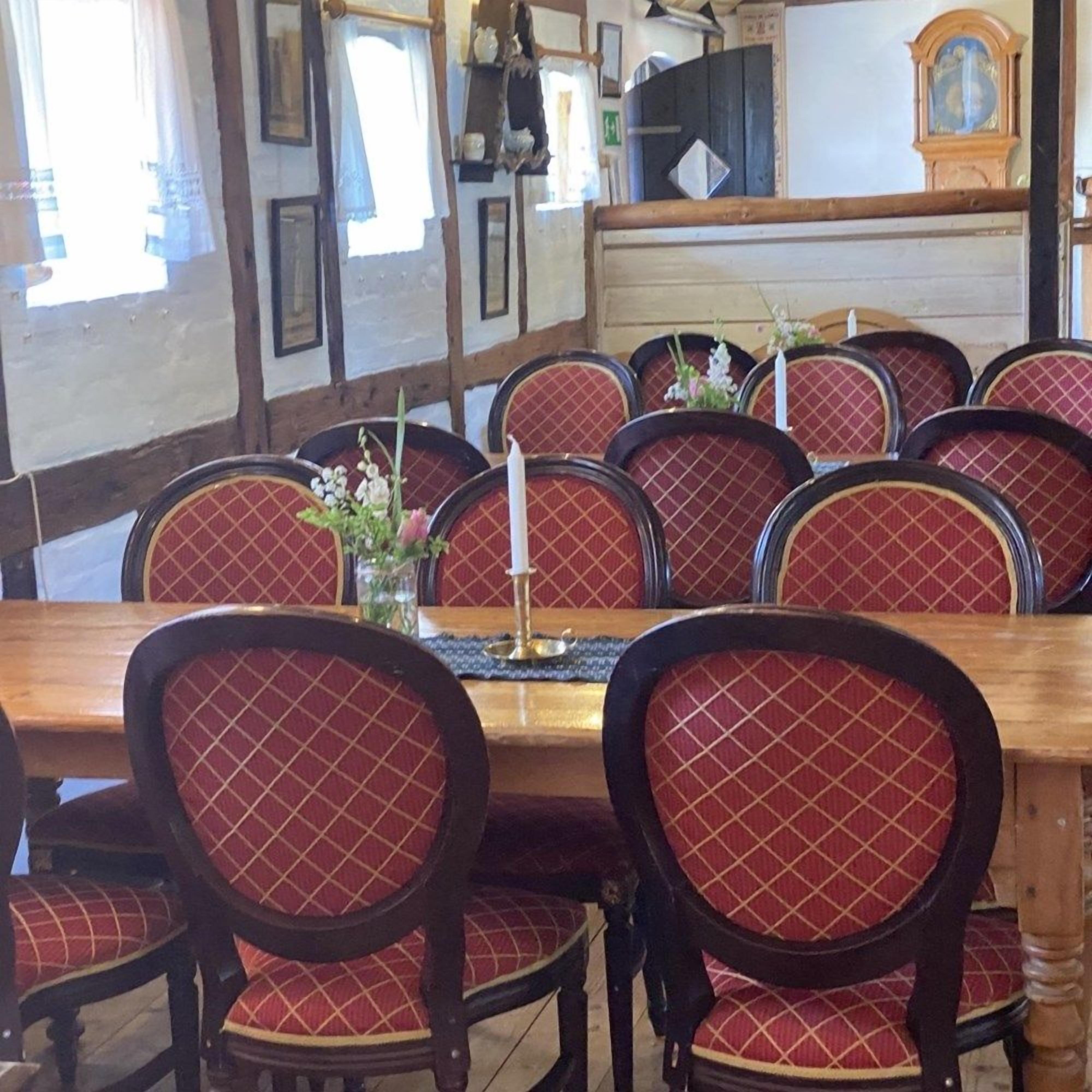 A dining area with a wooden table and red upholstered chairs.