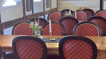 A dining area with a wooden table and red upholstered chairs.
