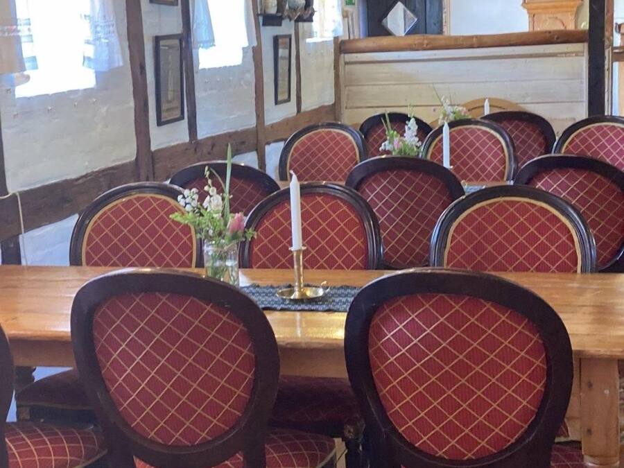 A dining area with a wooden table and red upholstered chairs.