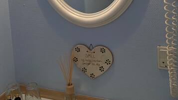 A bathroom with a round mirror, a towel rack, a vanity with a sink, and a hairdryer.