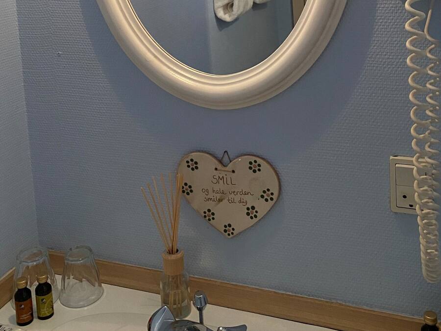 A bathroom with a round mirror, a towel rack, a vanity with a sink, and a hairdryer.