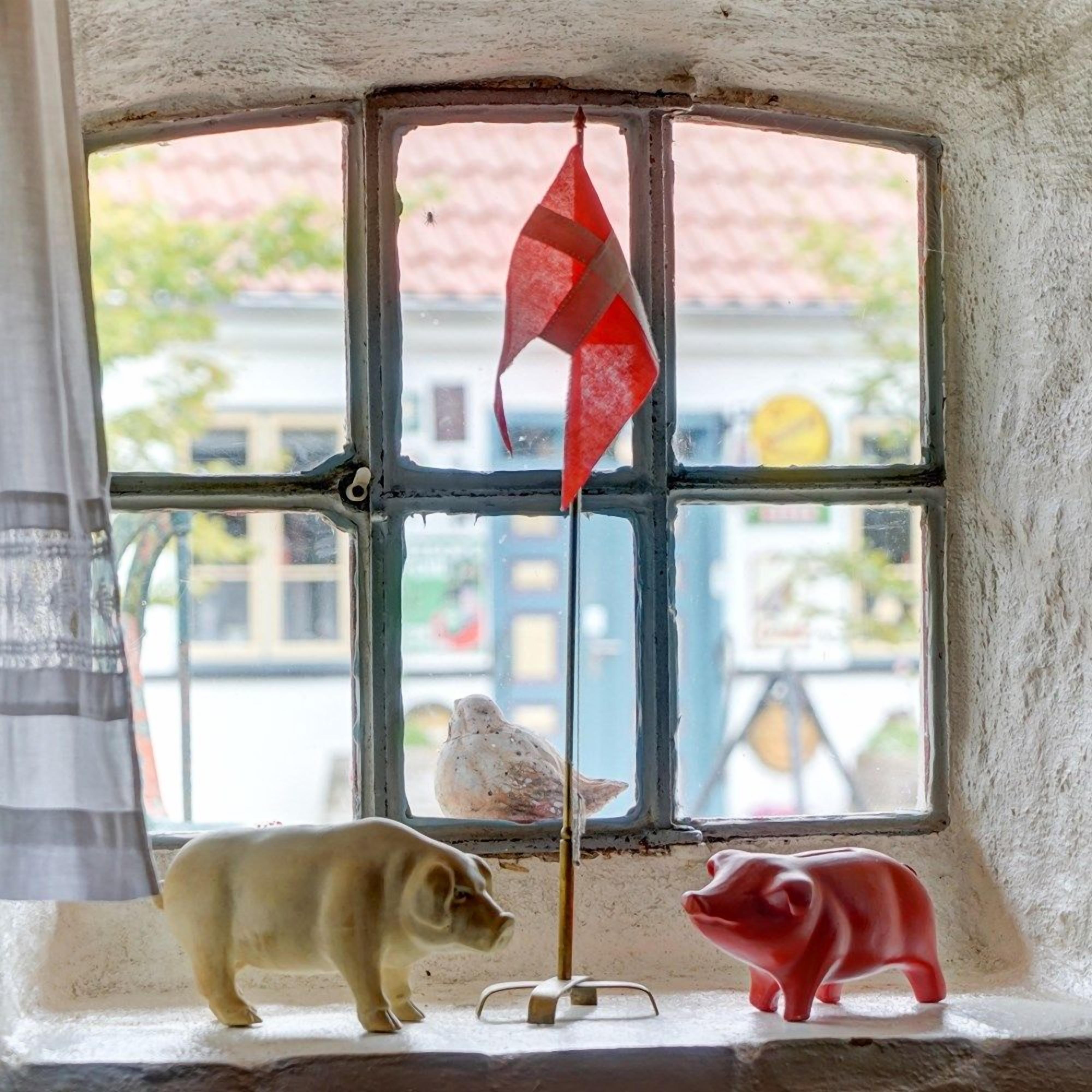Una ventana con vista a un edificio y una bandera roja.