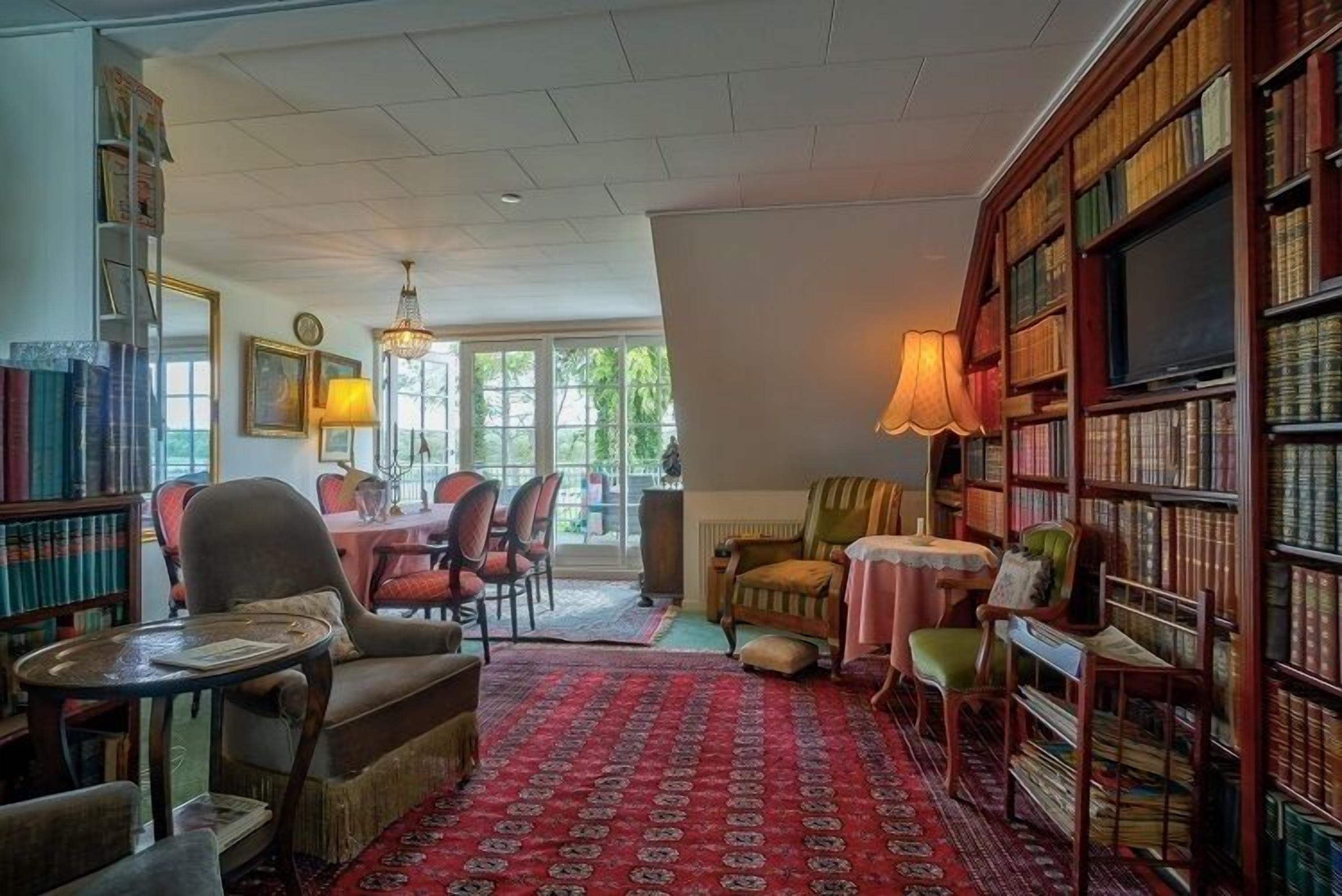 A cozy library with bookshelves, comfortable seating, and a large window.