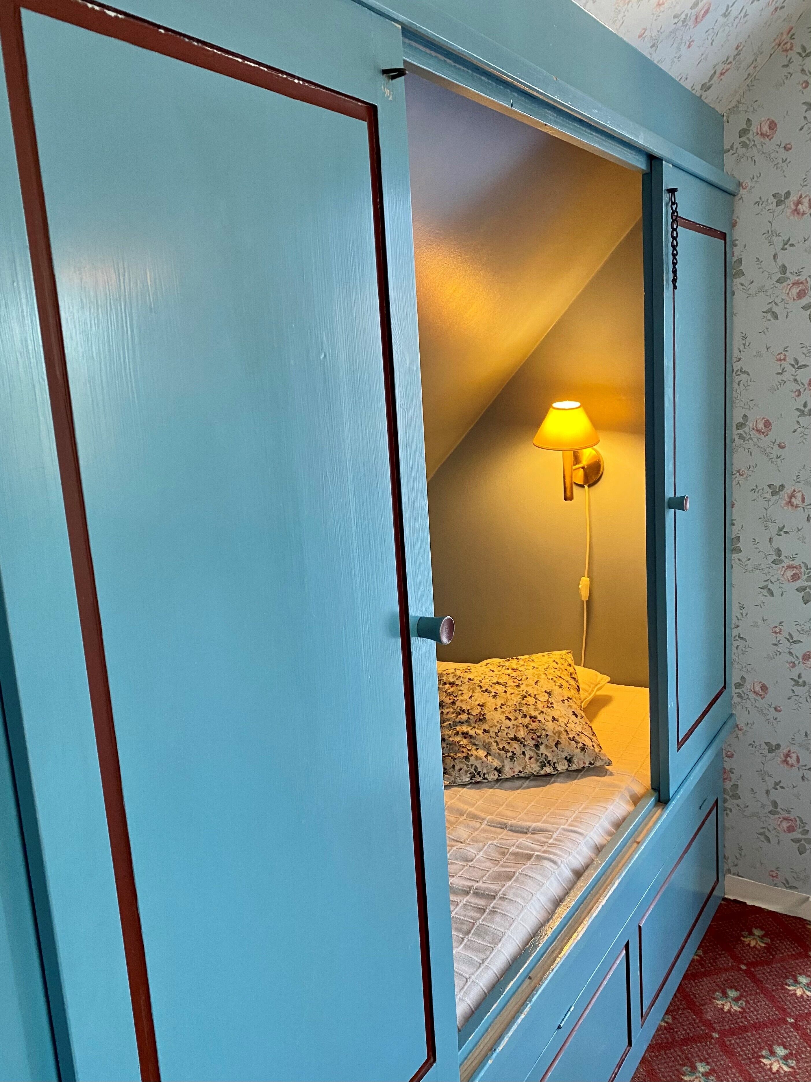 A bedroom with a bed, a nightstand, and a wall-mounted lamp.