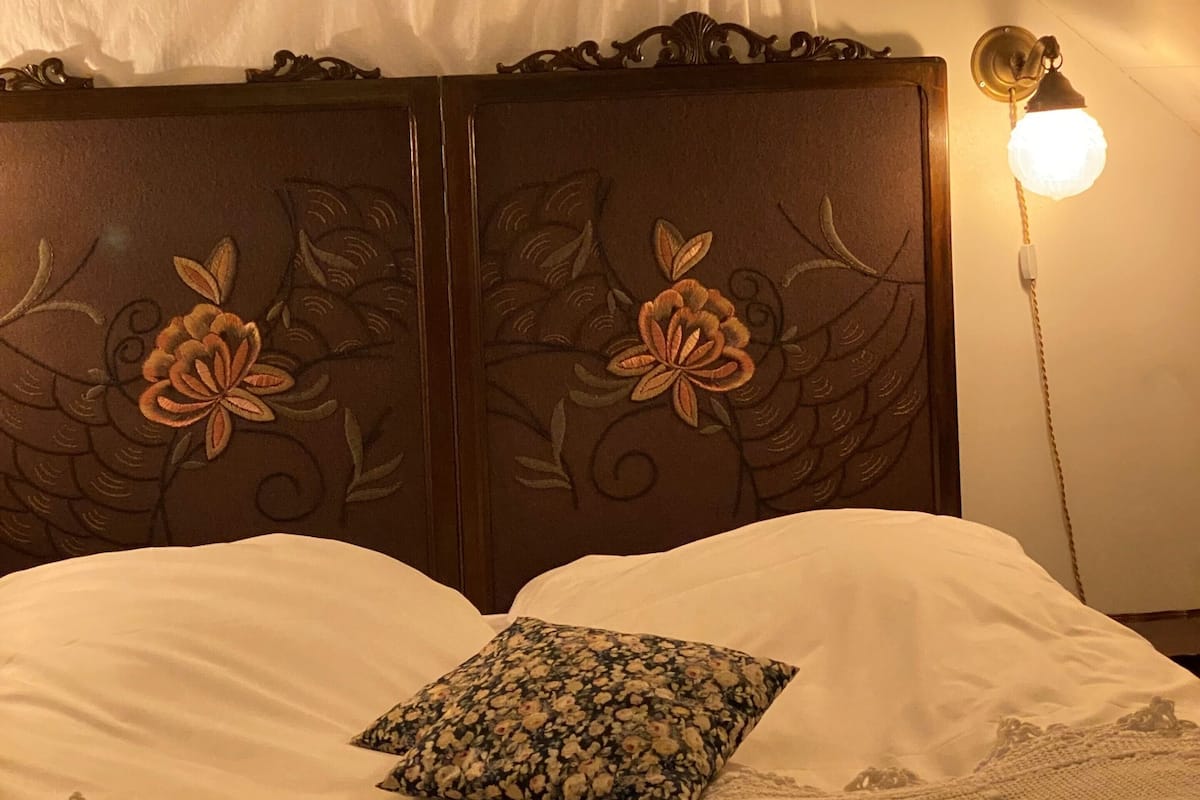 A bed with a floral-patterned pillow, a canopy, and a bedside lamp.