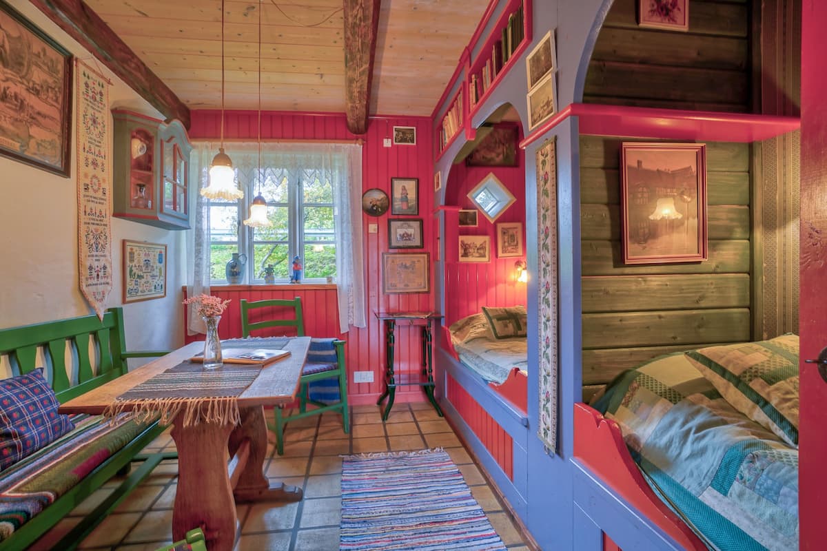 A cozy room with a wooden table, a green sofa, and a bed with a quilt.