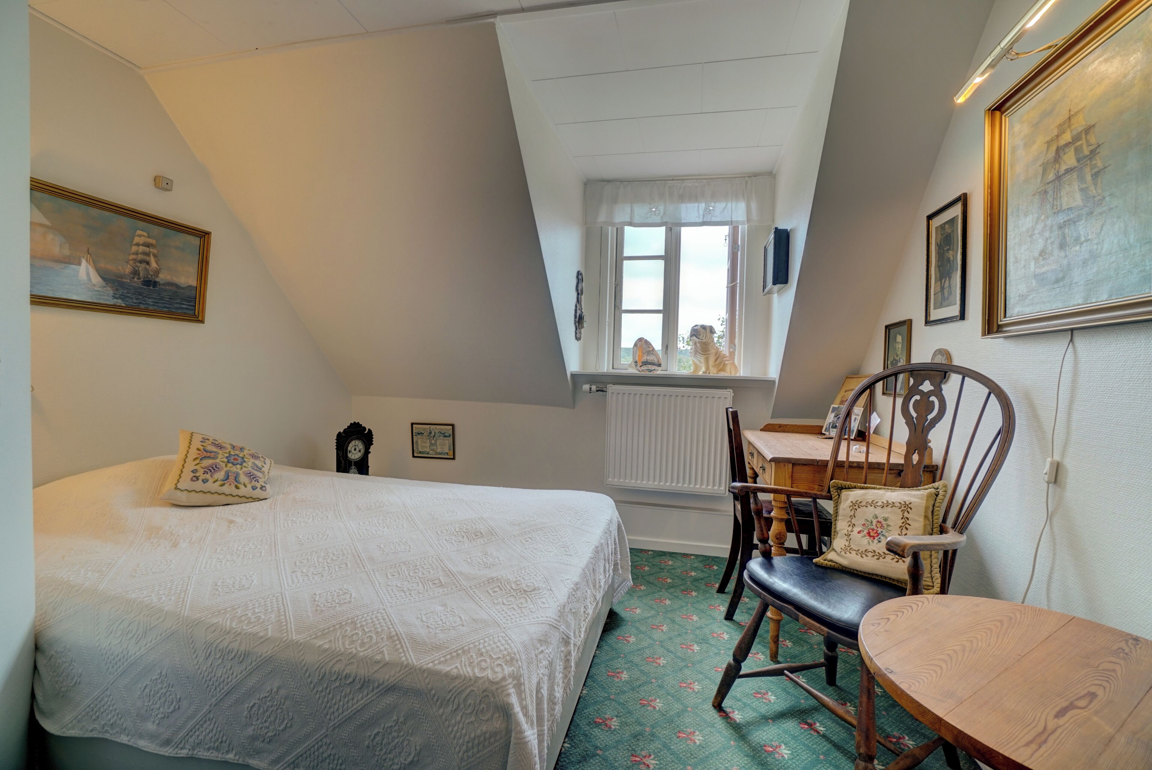 A bedroom with a bed, a chair, a table, and a window with a view.