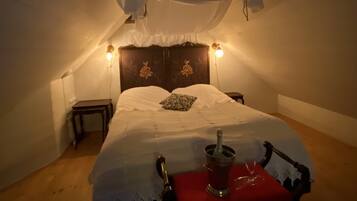 A bedroom with a bed, bedside lamps, a nightstand, and a chair with a red cushion.