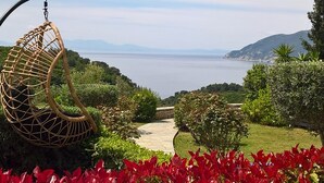 A hanging chair overlooking a scenic view of a body of water and mountains. - Villa Mirothea (Alonissos)