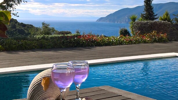 A pool with a wooden deck and two purple glasses on it. - Villa Mirothea (Alonissos)