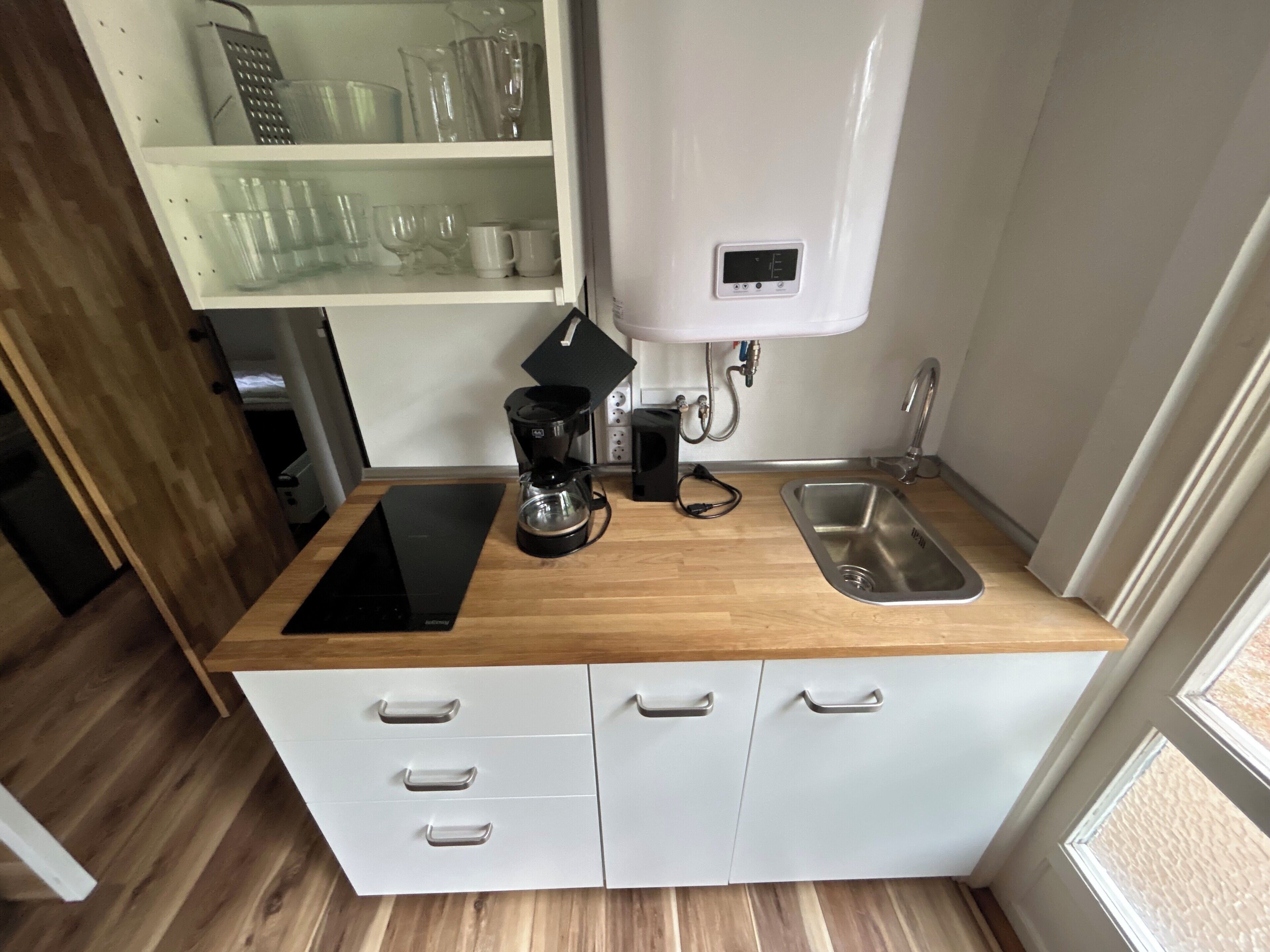 Cocina compacta con cafetera, un lavamanos y un mueble con cajones.