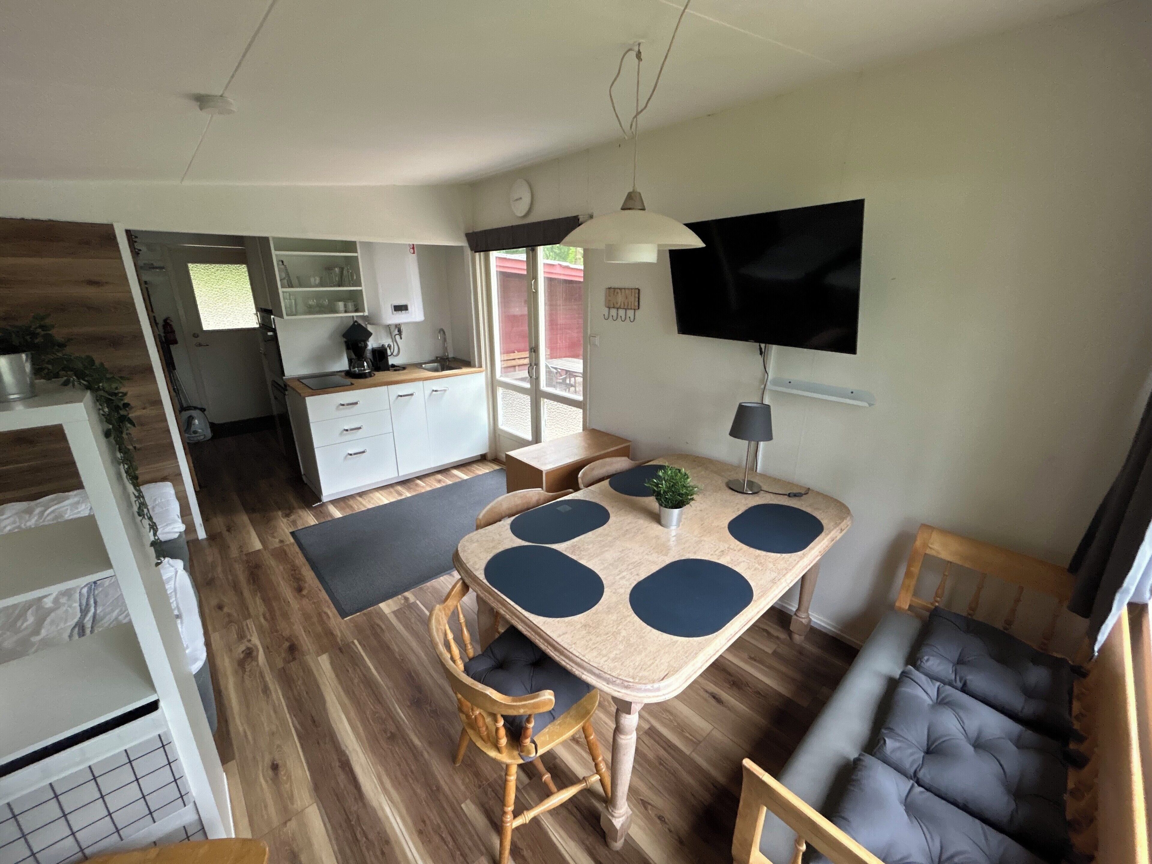 Un espacio habitable compacto con cocina, comedor y televisor montado en la pared.
