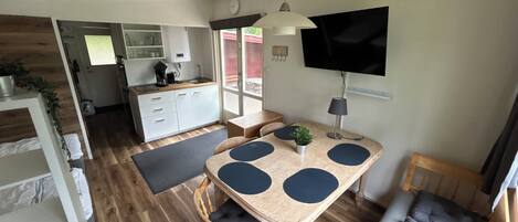 Un espacio habitable compacto con cocina, comedor y televisor montado en la pared.