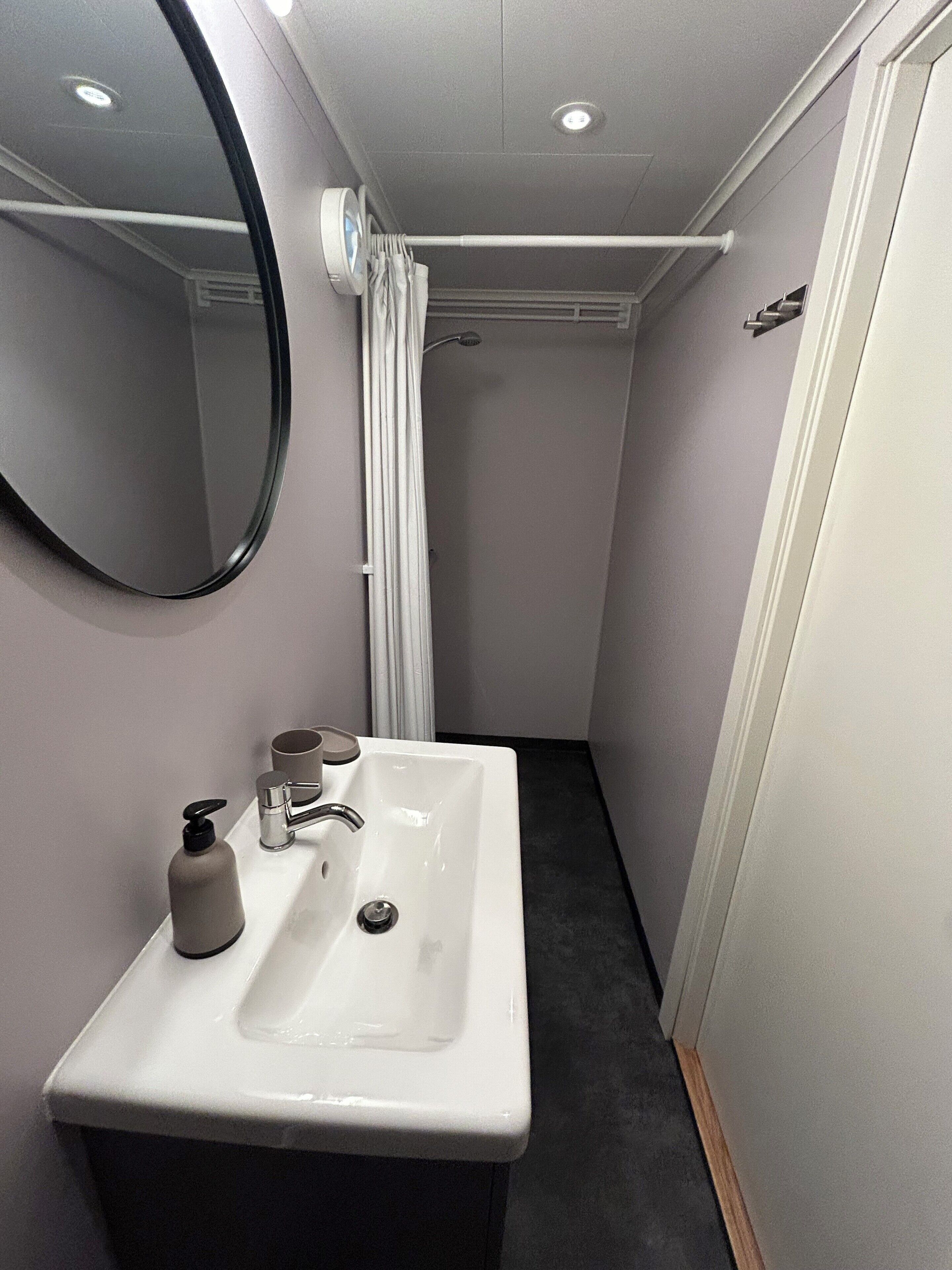 A bathroom with a white sink, a mirror, a shower curtain, and a towel rack.
