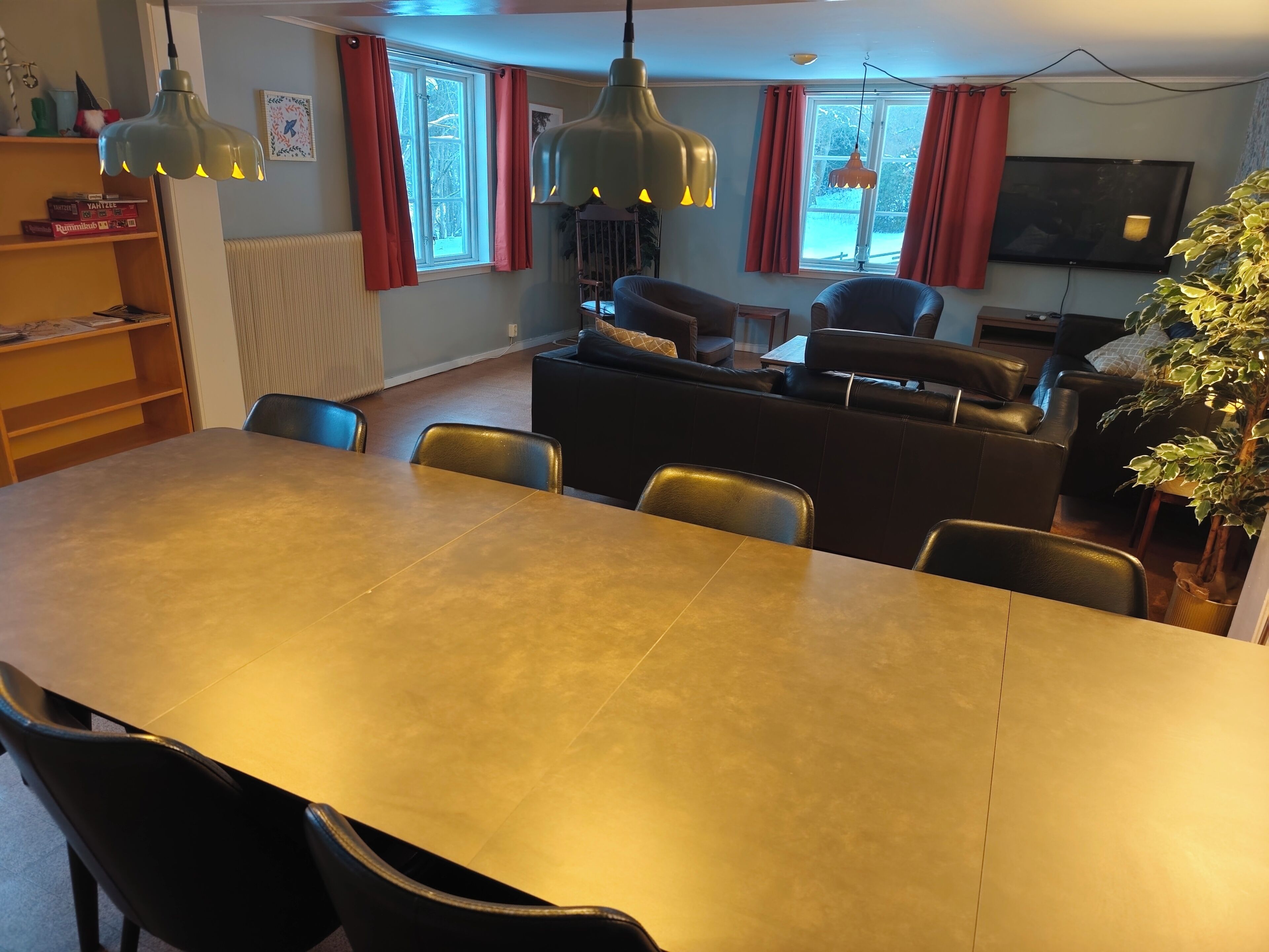 A dining area with a long table, black chairs, and two pendant lights.