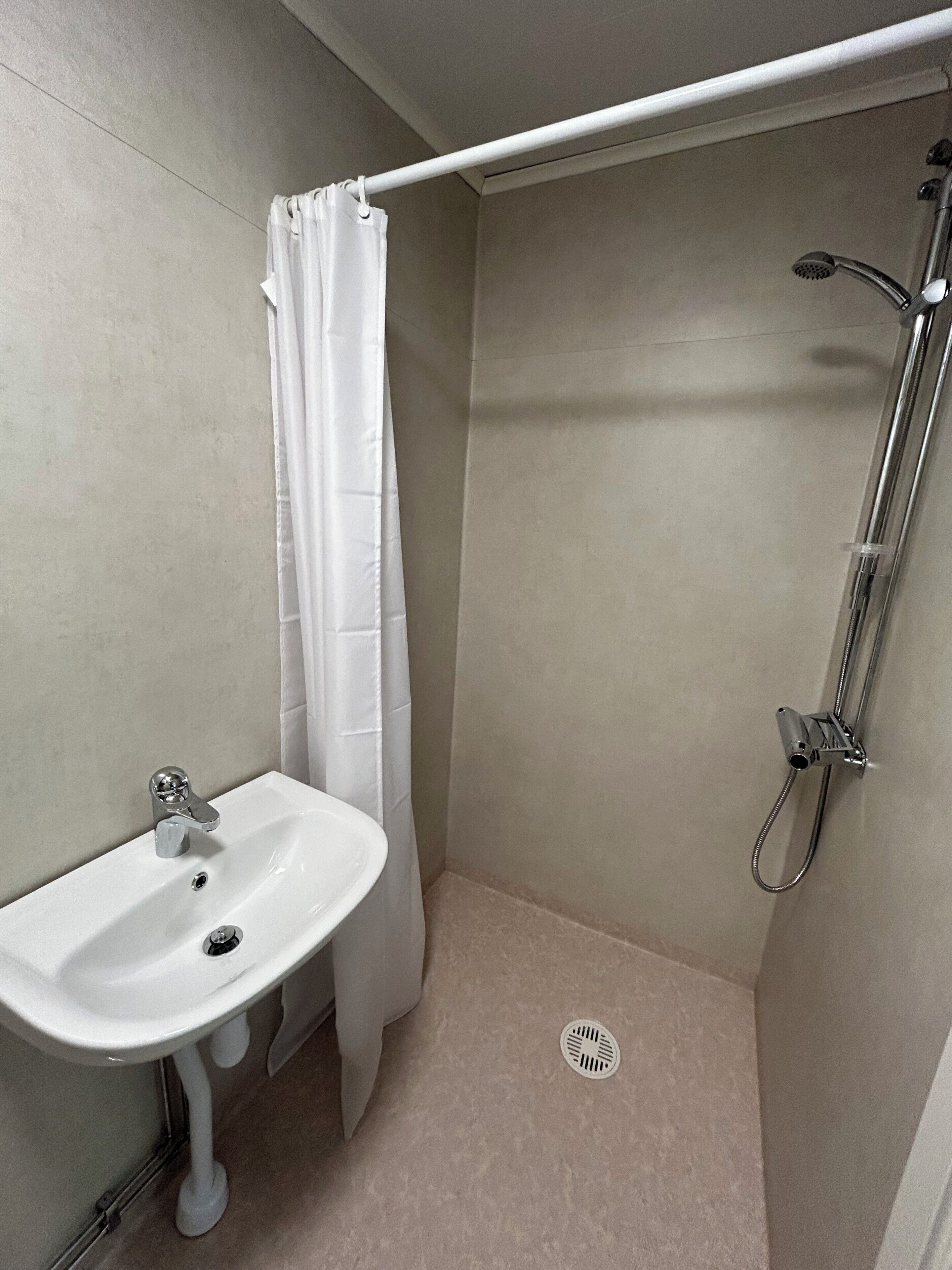 A bathroom with a shower, a sink, and a curtain.