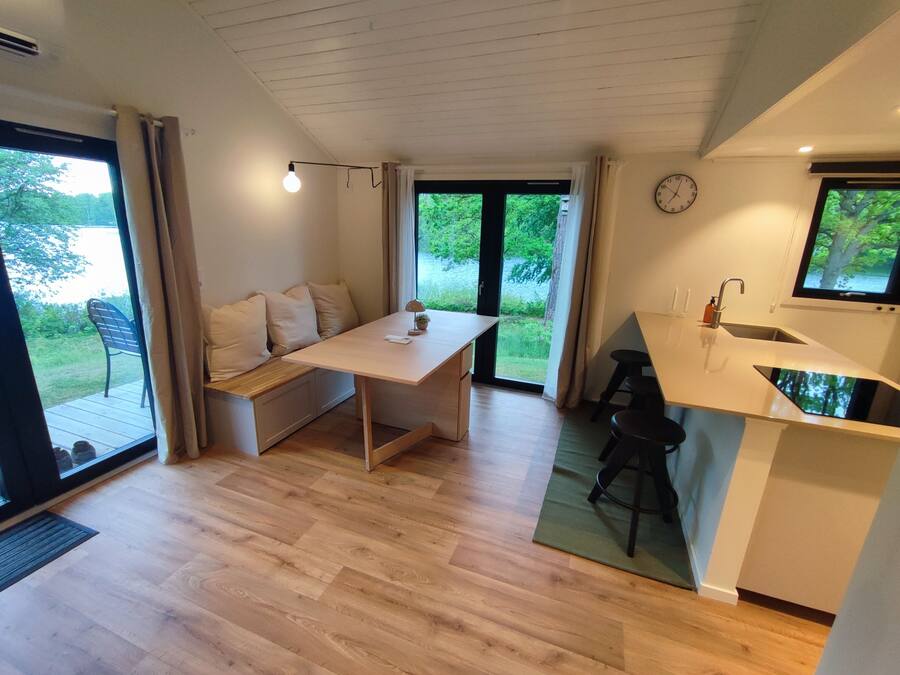A modern kitchen with a dining area, a sink, and a clock on the wall.