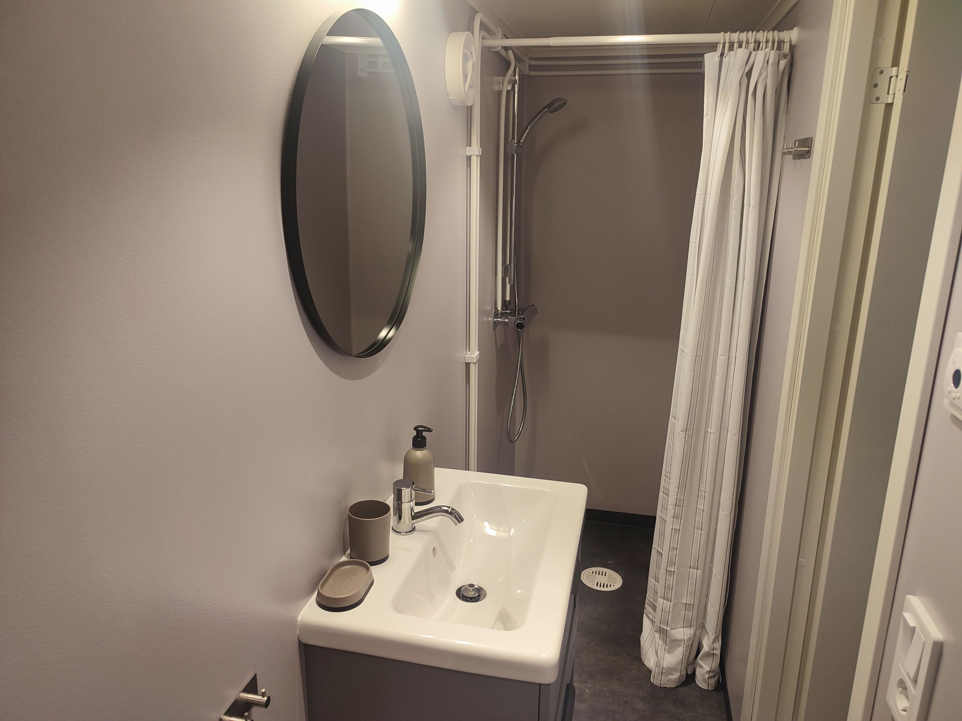 A bathroom with a sink, mirror, shower, and toilet.