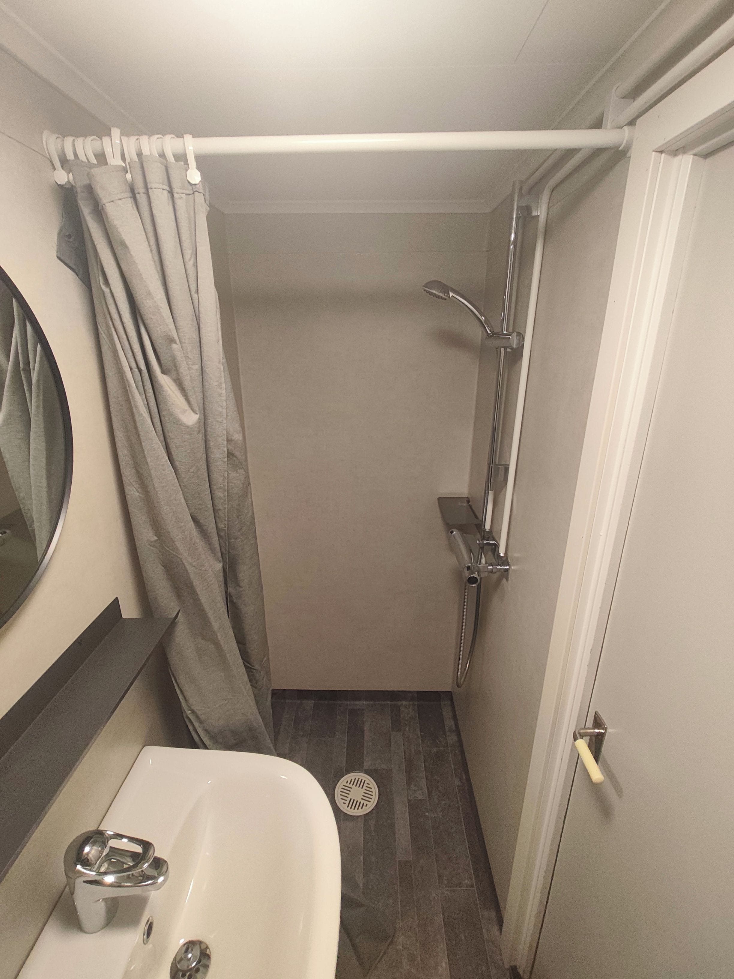 A compact bathroom with a shower, a sink, and a toilet.