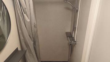 A compact bathroom with a shower, a sink, and a toilet.