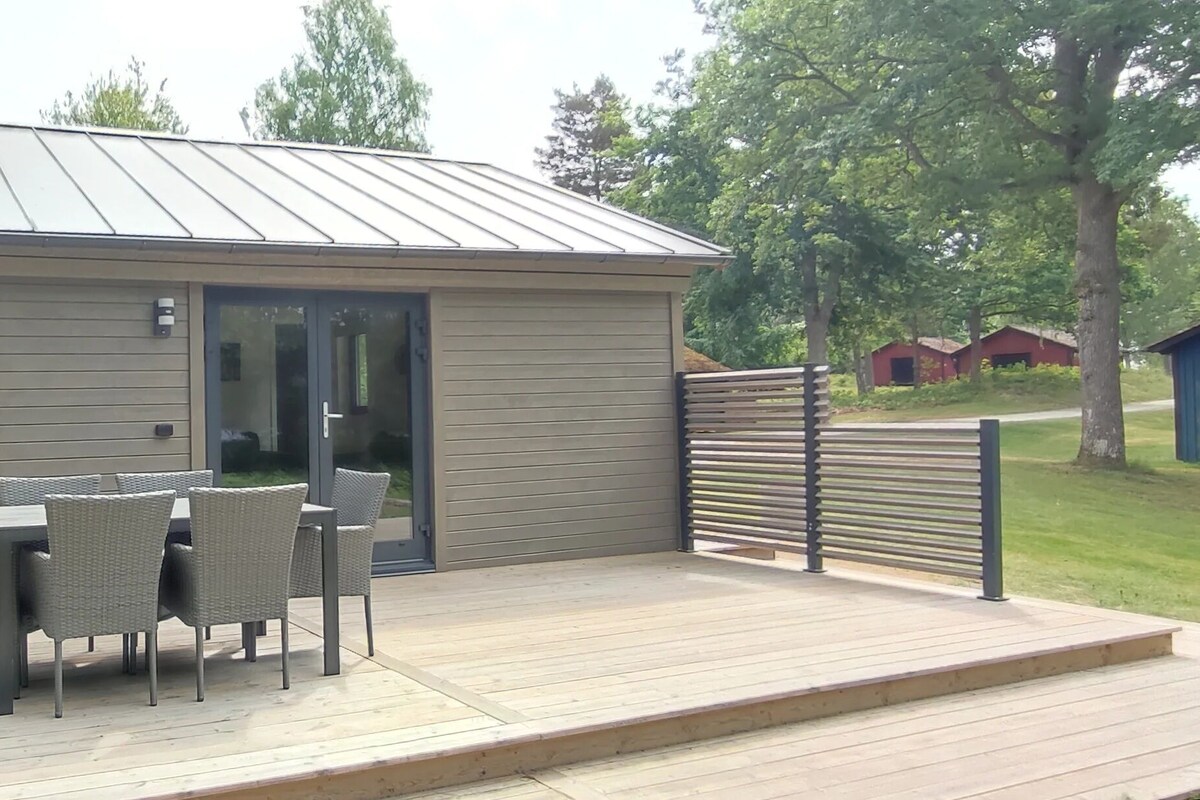 A modern outdoor structure with a deck, a table with chairs, and a sliding glass door.