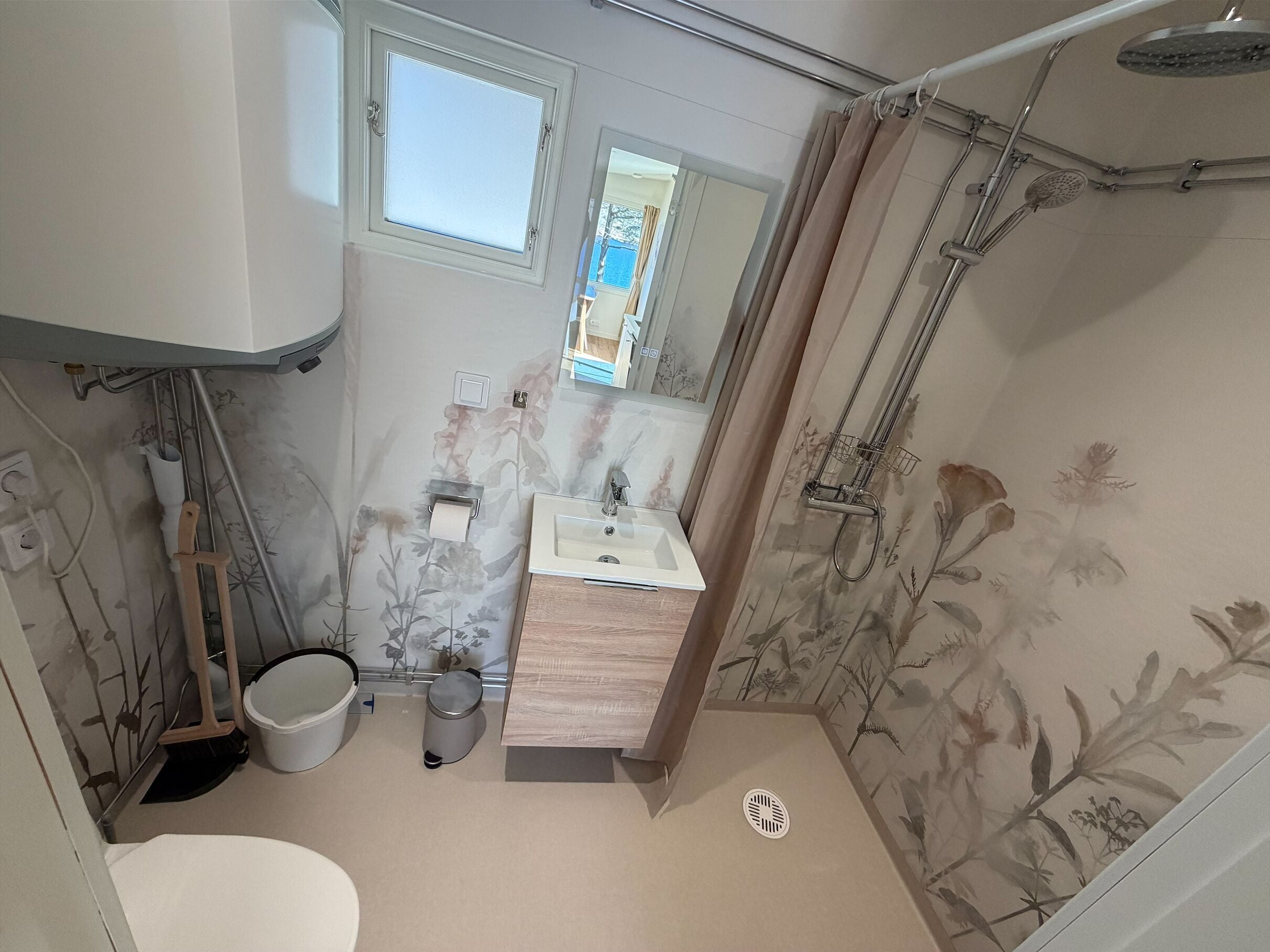Un baño con ducha, inodoro, lavabo y ventana.
