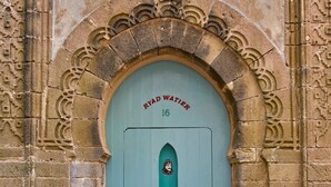 A door with the inscription "RYAD WATIER 16" and a small window with a figure. - Ryad Watier (Essaouira)