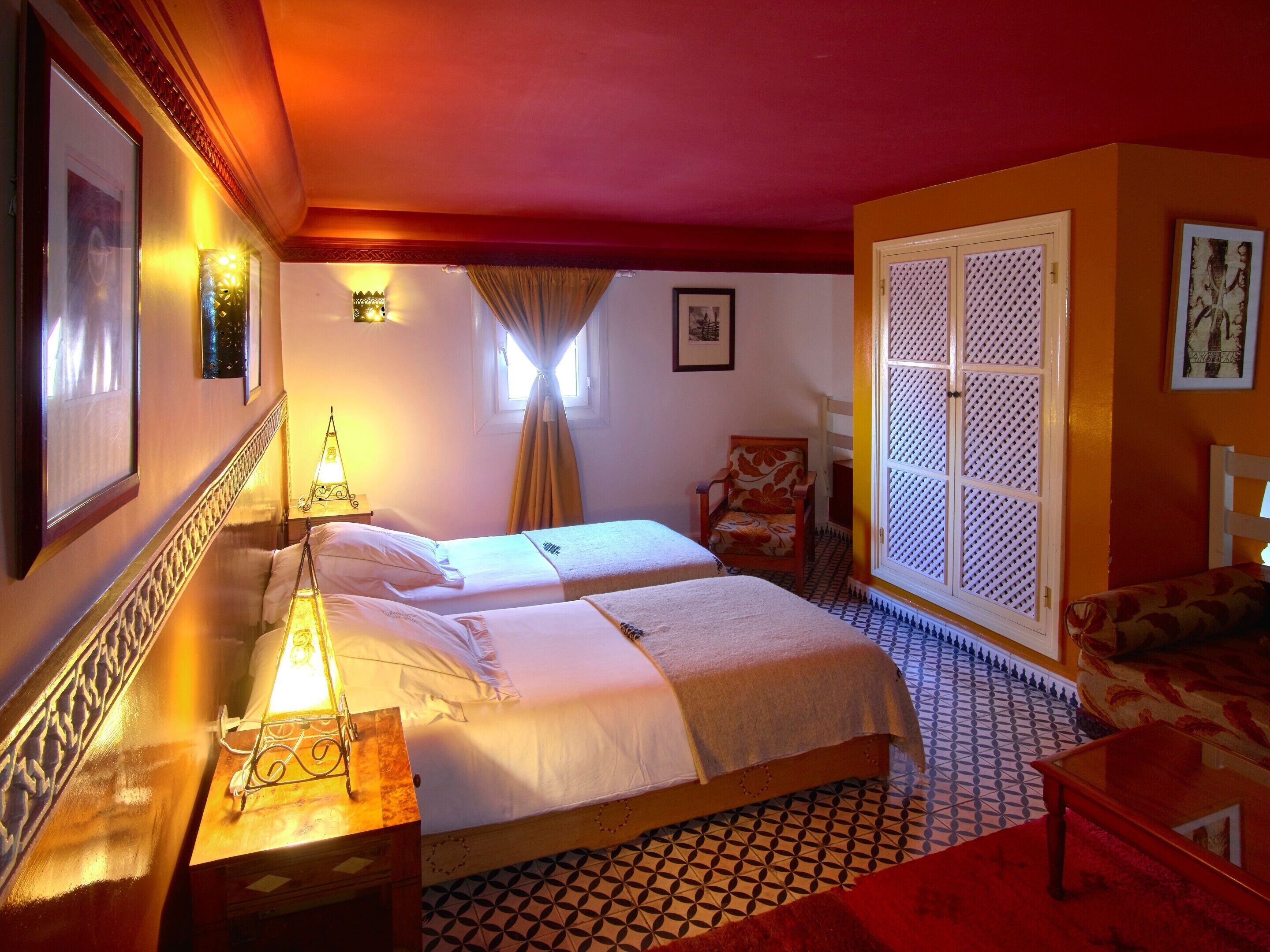 A hotel room with two beds, a sitting area, and a decorative wall.