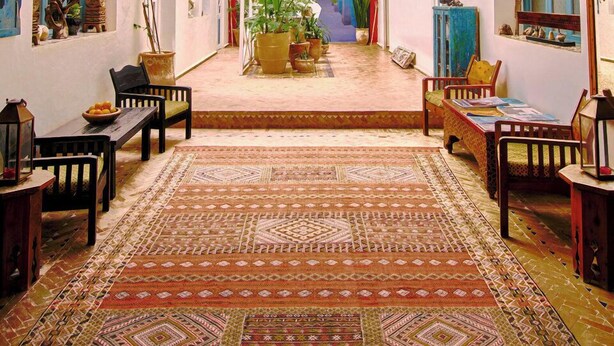 A spacious interior with a central staircase, multiple seating areas, and a variety of potted plants. - Ryad Watier (Essaouira)