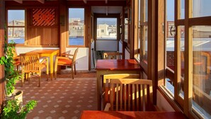 A sunlit room with wooden furniture, large windows, and a view of the city. - Ryad Watier (Essaouira)