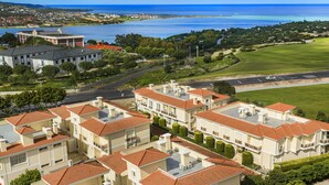 A coastal residential area with multiple buildings featuring red-tiled roofs and a view of the ocean. - Kamer Exclusive Hotel & Suites (Cesme)