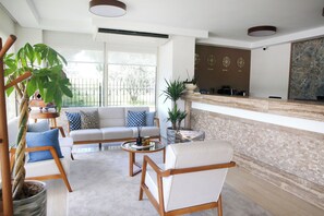 A modern living room with a sofa, armchairs, a coffee table, and a potted plant. - Kamer Exclusive Hotel & Suites (Cesme)