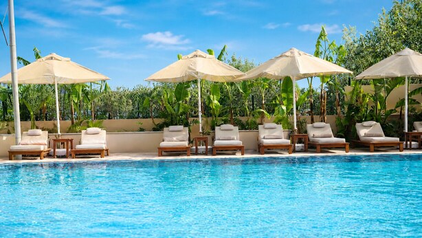 A swimming pool with lounge chairs and umbrellas. - Kamer Exclusive Hotel & Suites (Cesme)