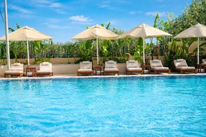 Una piscina con sillones de descanso y sombrillas.