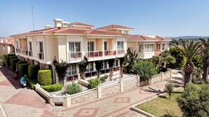 A multi-story building with a balcony, a paved driveway, and a sign indicating a cafe and restaurant. - Kamer Exclusive Hotel & Suites (Cesme)