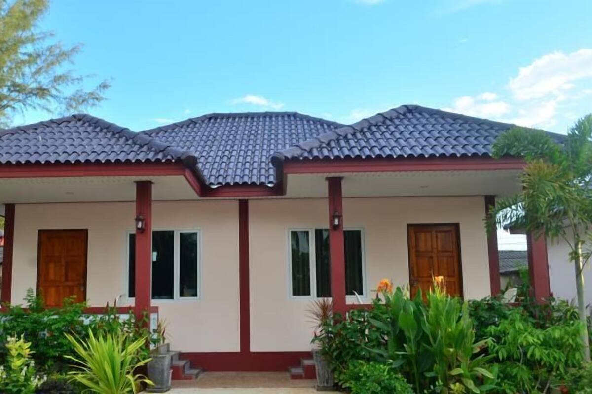 A two-story house with a tiled roof, a central entrance, and a garden with various plants.