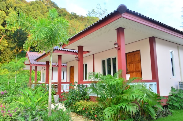 A two-story building with a red and white exterior, surrounded by lush greenery and a variety of plants. - Selamat Lanta Resort (Ko Lanta)