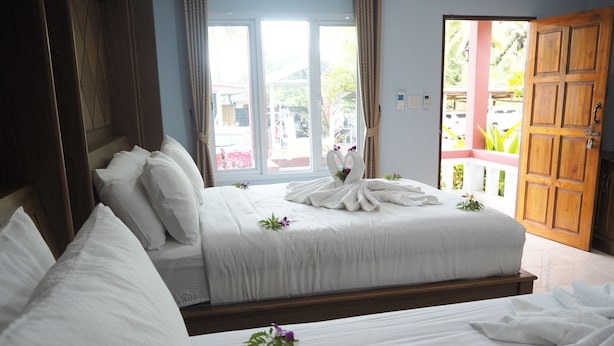 Habitación de hotel con dos camas, una puerta de madera y vistas al exterior.