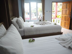 A hotel room with two beds, a wooden door, and a view of the outside. - Selamat Lanta Resort (Ko Lanta)