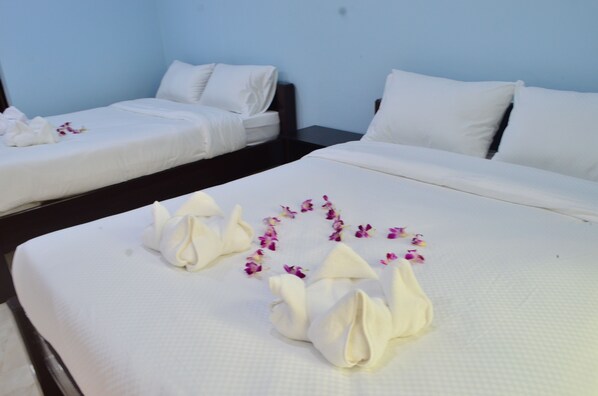 A hotel room with two beds, each with white linens and pillows, and a decorative arrangement of white towels and purple flowers on the bed in the foreground. - Selamat Lanta Resort (Ko Lanta)