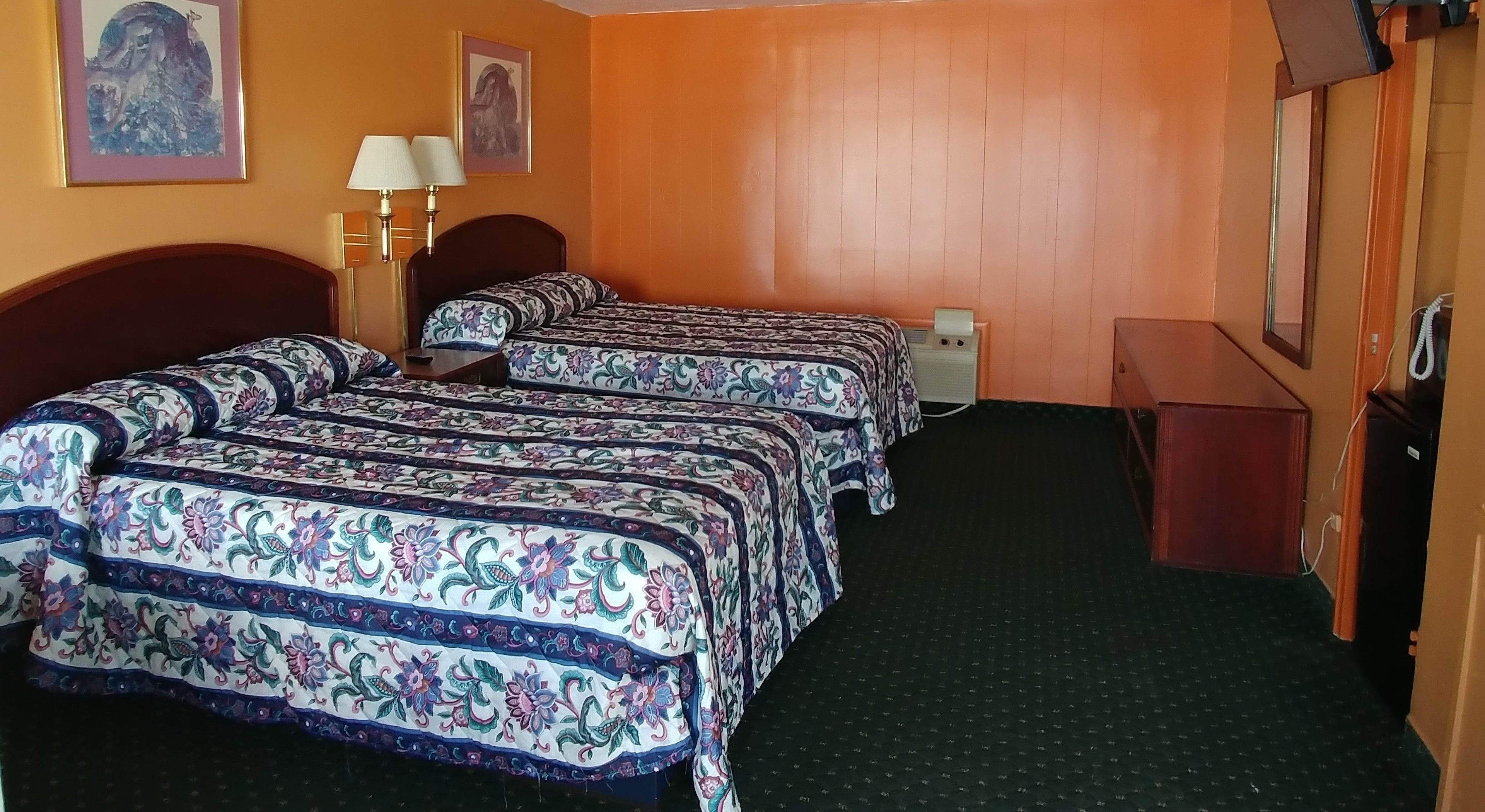 A hotel room with two beds, a desk, a chair, a lamp, and a telephone.