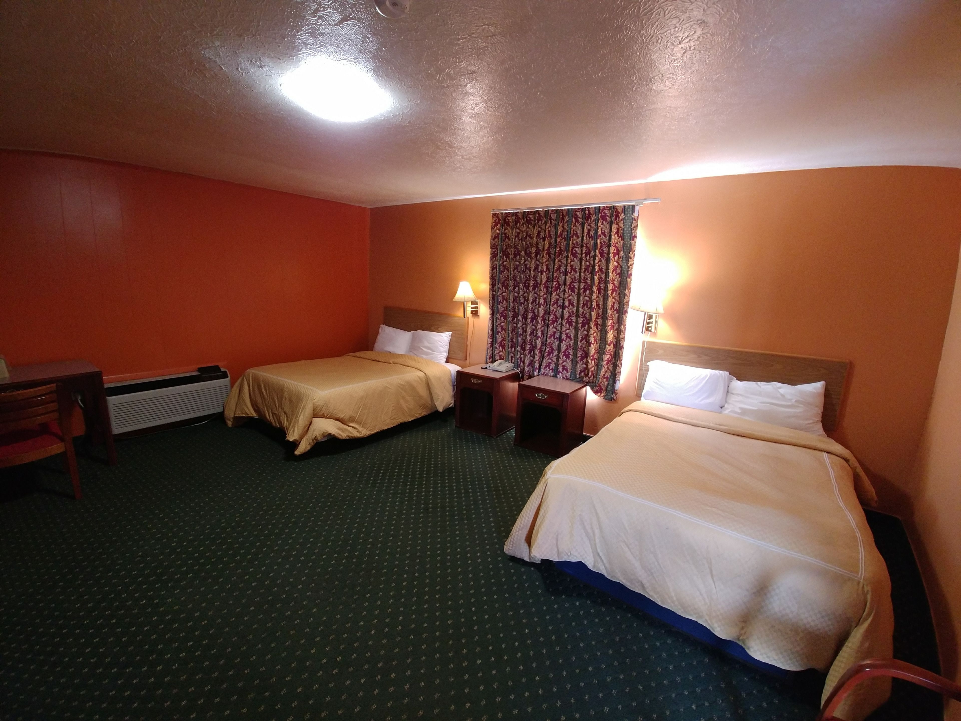A hotel room with two beds, a desk, and a chair.