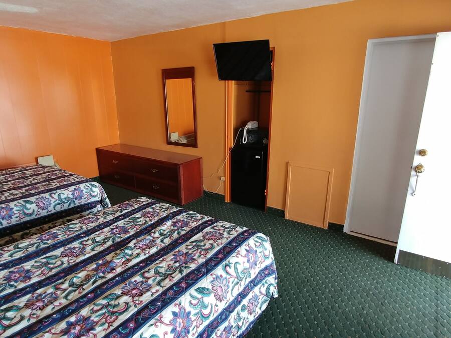 Una habitación de hotel con dos camas, un aparador, un televisor y un armario.