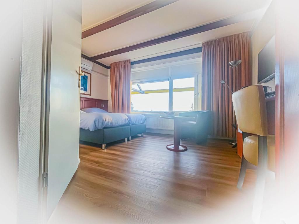 A hotel room with a bed, a sofa, a table, and a chair.